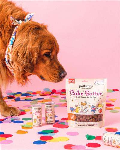 Banana Soft & Chewy Dog Treats Mini Tube with peanut butter, surrounded by a curious dog.