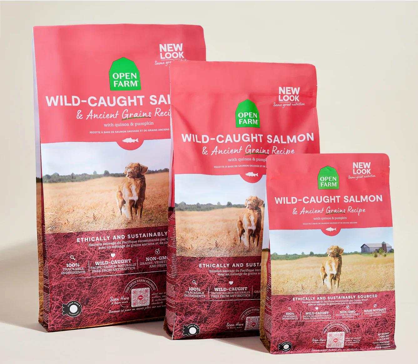 Three bags of Open Farm Wild-Caught Salmon & Ancient Grain Recipe dog kibble with a dog running in a field on the packaging