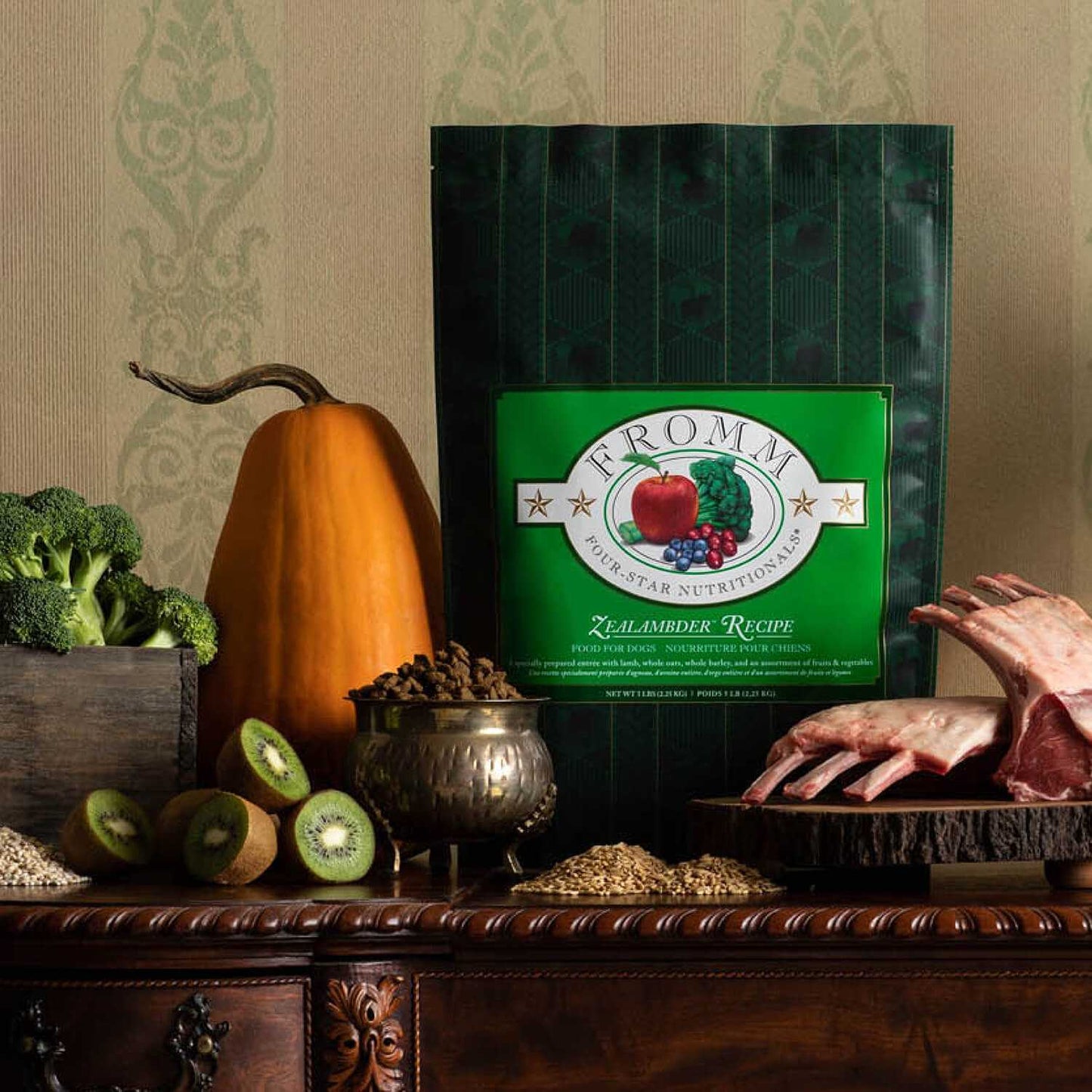 Zealambder Dog Food package with fresh fruits, vegetables, grains, and raw lamb ribs on wooden surface