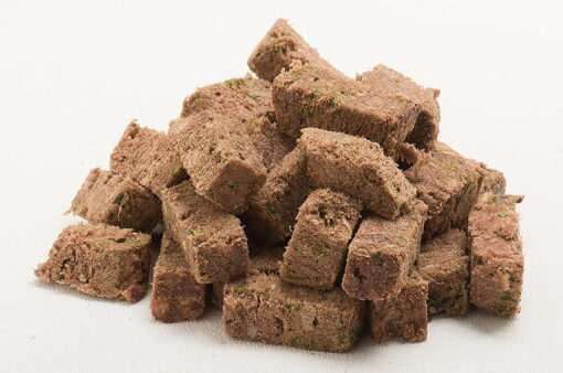 Freeze-Dried Dog Food in brown, porous meat chunks, piled in irregular cube shapes with a coarse, crumbly texture.