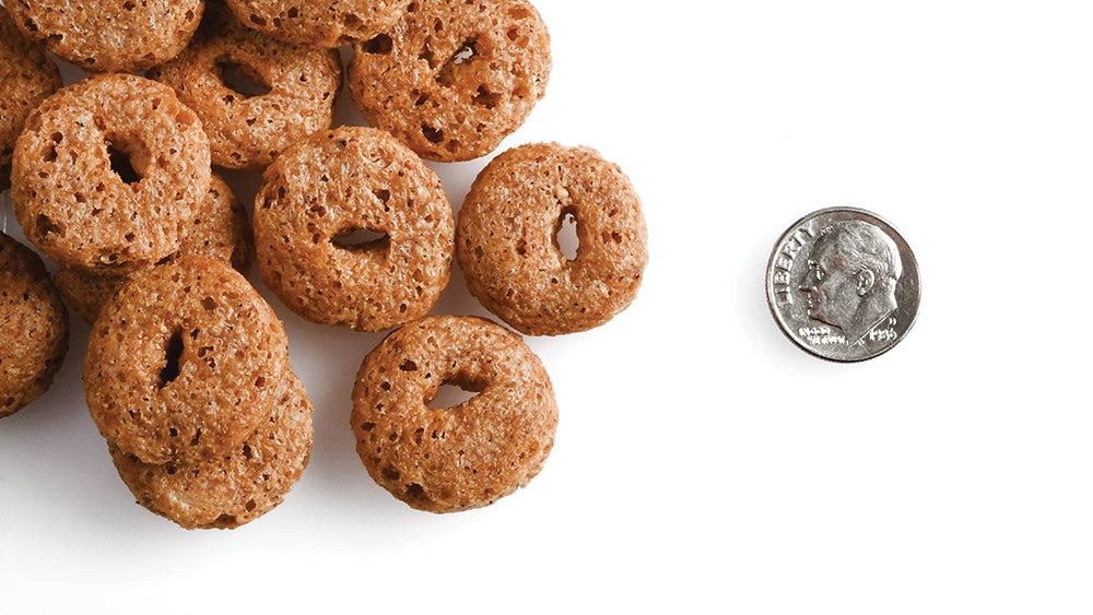 CRUNCH O's Peanut Butter Jammers dog treats next to a coin for size reference.
