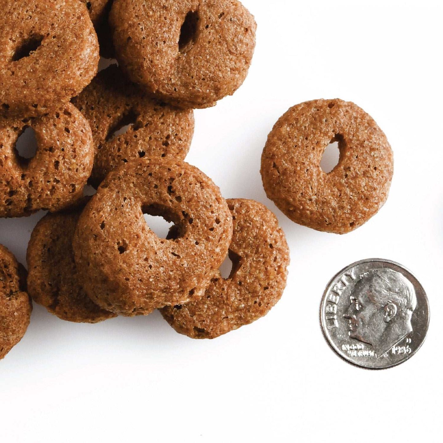 Crunchy dog treats, Pot Roast Punchers, next to a coin for size comparison.