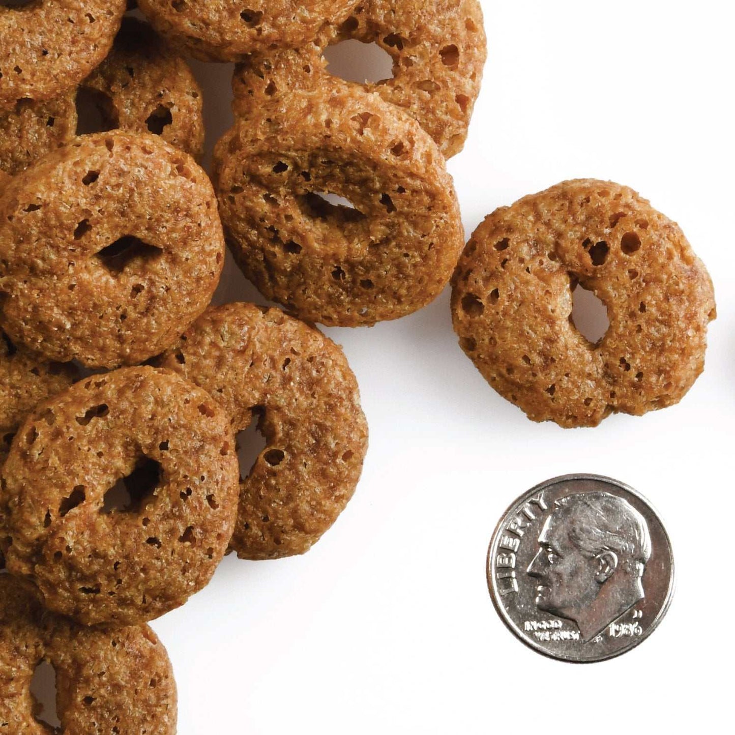 Pumpkin Kran Pow dog treats with crunchy texture next to a dime for size comparison.