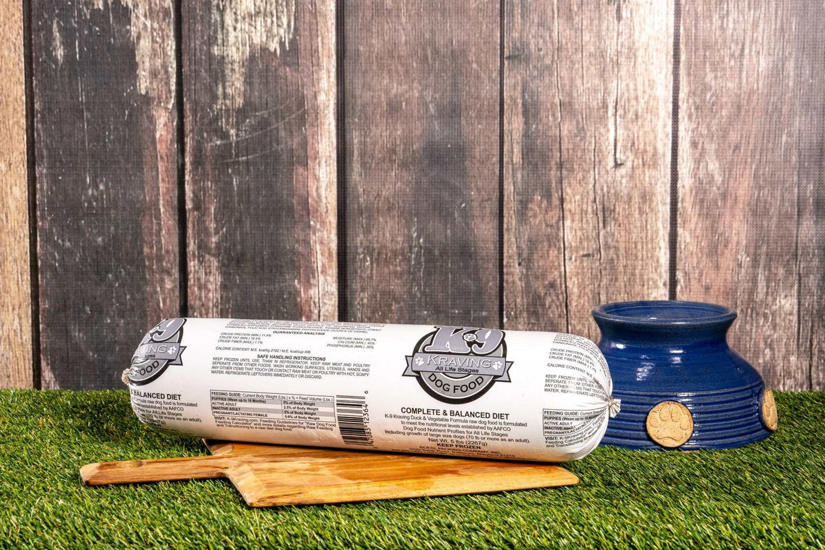K-9 Kraving Duck & Vegetable Formula Raw Dog Food on wooden board with feeding bowl.