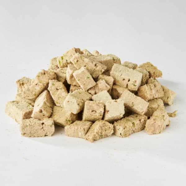 Freeze dried chicken dog food in cube form on a white background.