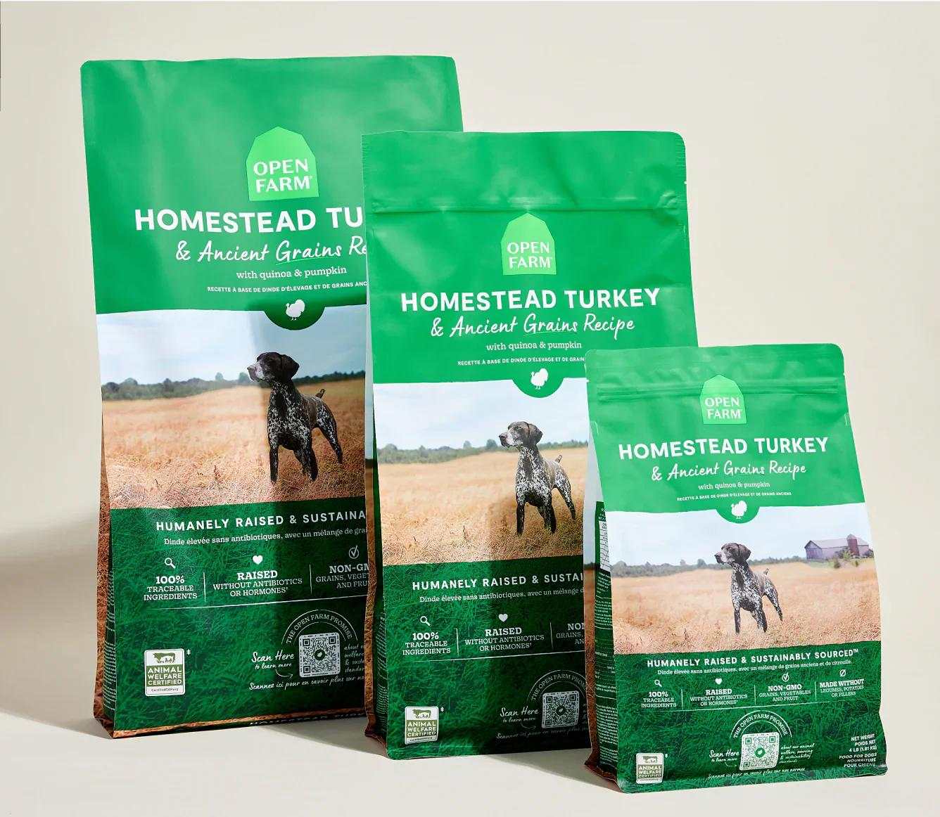 Three green bags of Homestead Turkey & Ancient Grain Recipe dog kibble featuring a hunting dog image and sustainable, humanely raised ingredients.