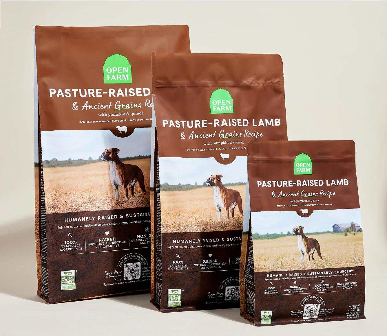 Three bags of Open Farm Pasture-Raised Lamb & Ancient Grain Recipe dog kibble featuring a dog in a field on the packaging.