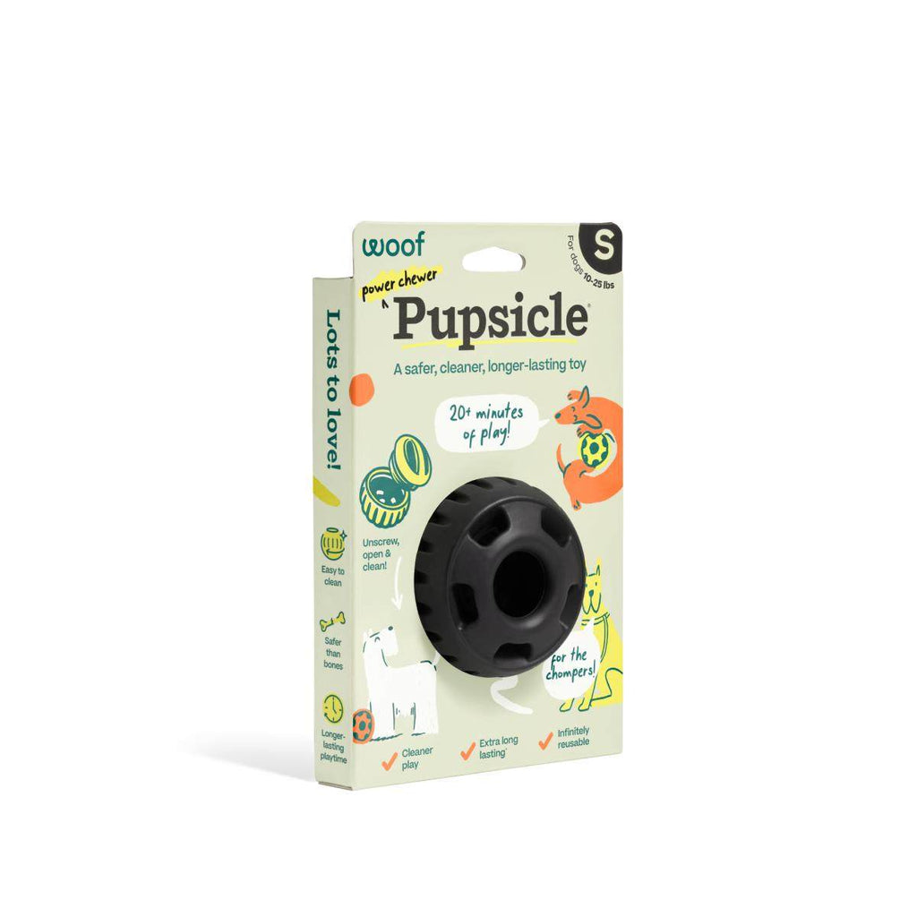 Pupsicle dog enrichment toy, black natural rubber with a round, slotted design, packaged in a colorful illustrated box.