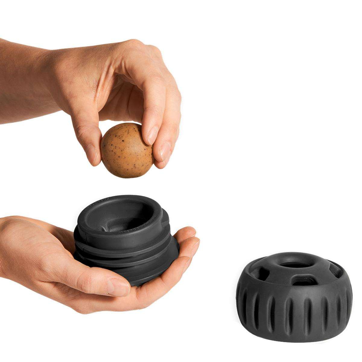 Pupsicle dog enrichment toy in black rubber, shown in two parts with a rounded treat ball and slotted base.