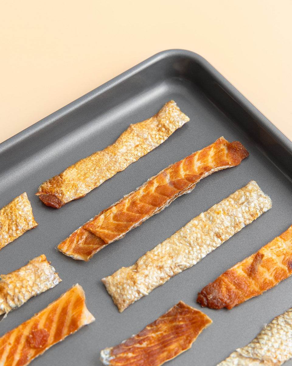 Salmon Skin Jerky strips laid out on a dark tray, showcasing crispy smoked texture