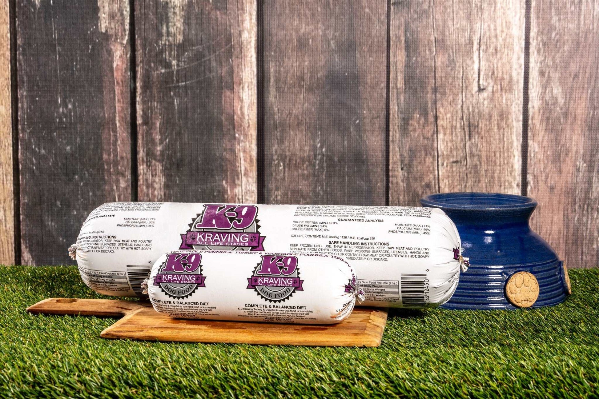 K-9 Kraving Turkey & Vegetable Formula Raw Dog Food on a wooden board next to a blue dog bowl, with grass and wooden background.