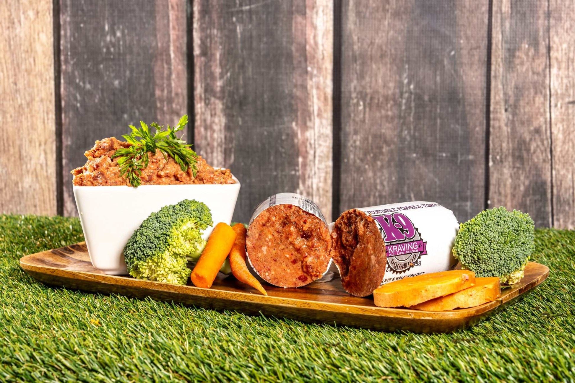 Turkey and vegetable raw dog food with broccoli, carrots, and sweet potatoes on a wooden tray.