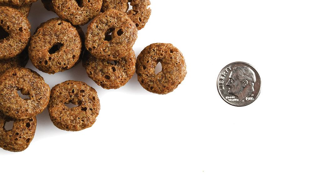 CRUNCH O's Blueberry Blasts dog treats next to a dime for size comparison on a white background.