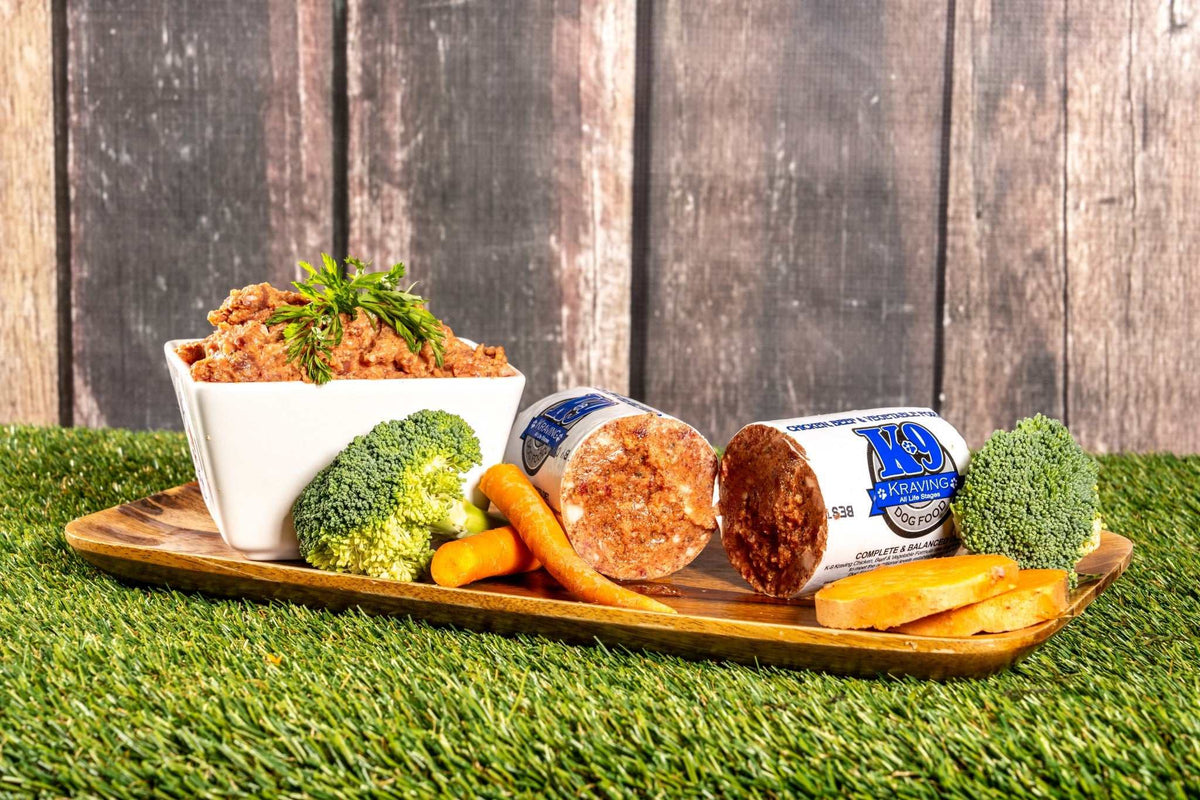 K-9 Kraving Chicken Beef & Vegetable Formula Raw Dog Food with broccoli, carrots, and sweet potatoes displayed on a tray.