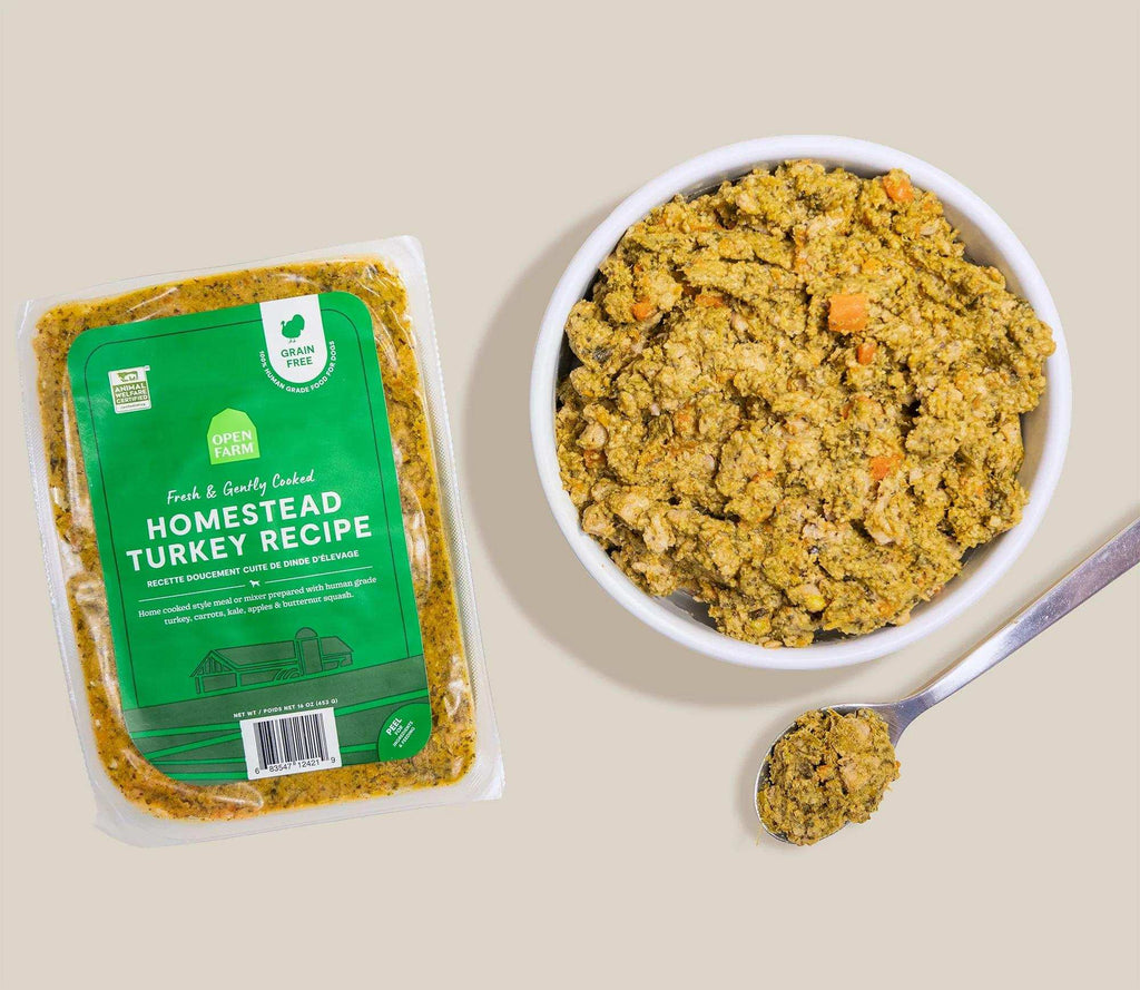 Homestead Turkey Grain-Free dog food in a sealed tray with a green label, shown as chunky cooked food in a bowl and spoon.