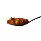 Lua's Golden Paste fermented vegetable blend, a chunky golden-orange paste with a moist, textured appearance on a spoon.