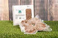 Mackerel & Vegetable Raw Dog Food packs on grass, eco-friendly packaging.