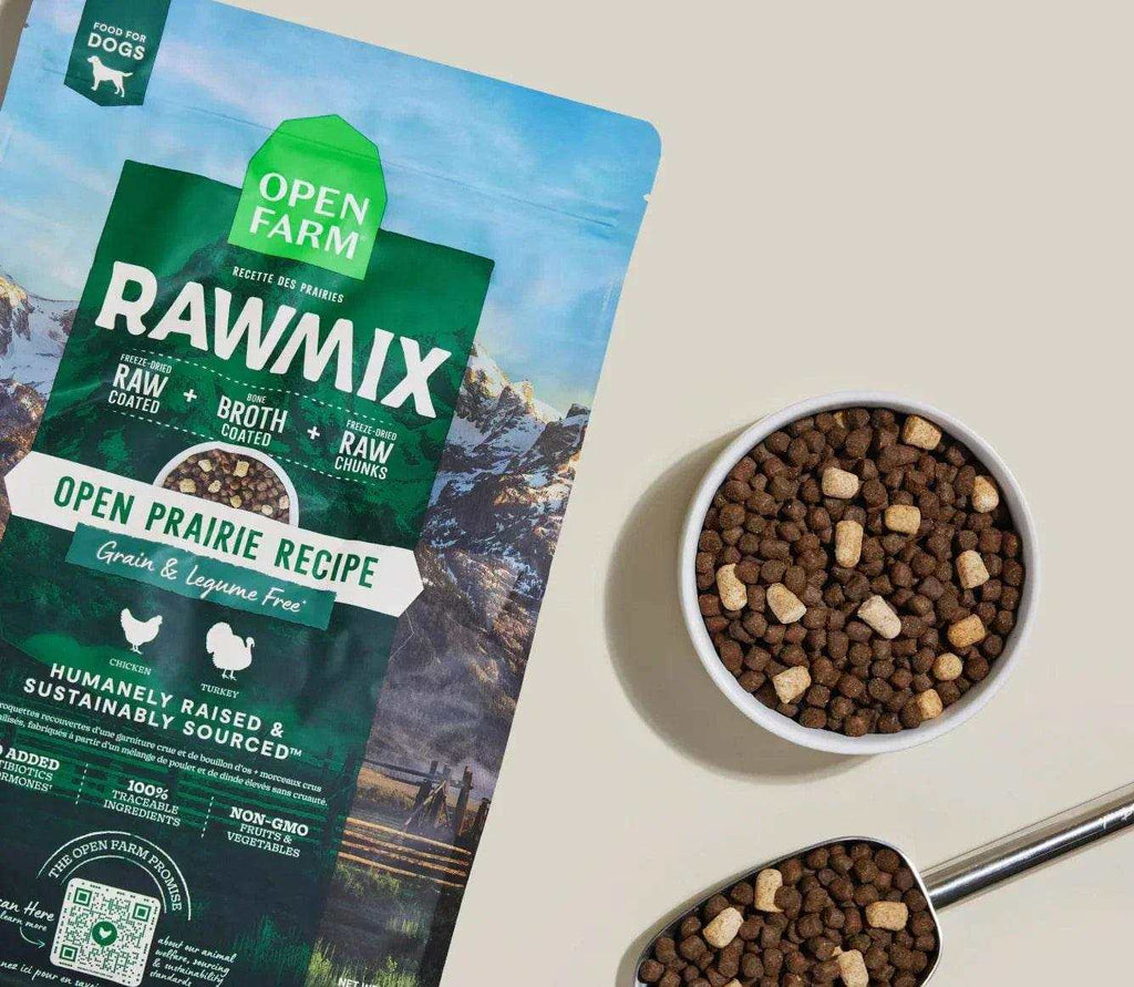 Grain-free dog kibble with brown nuggets and pale freeze-dried chunks, beside RawMix Open Prairie packaging.