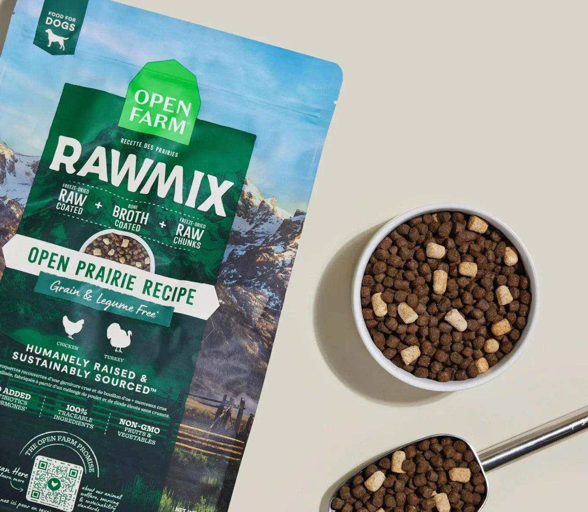 Grain-free dog kibble with brown nuggets and pale freeze-dried chunks, beside RawMix Open Prairie packaging.
