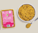 Wild-Caught Fish dog food, golden-brown freshly crafted mash in a sealed package with a bowl and spoonful of food.